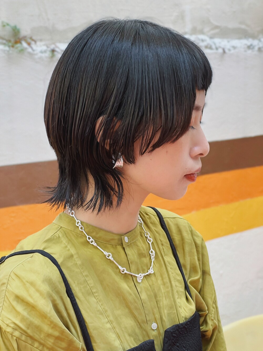 ベージュ系のトートバッグ、ベージュ系のキャミソール、グリーン系のトップスを着用したレディースの秋コーディネートの2枚目の写真