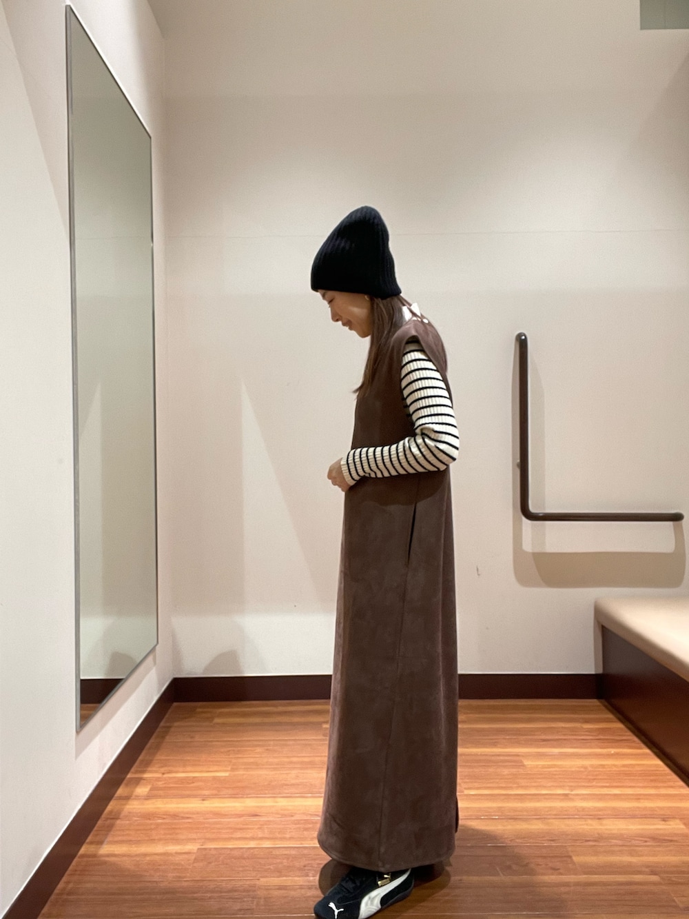 ブラウン系のワンピース、その他のニット/セーター、ブラック系のスニーカーを着用したレディースの冬コーディネートの2枚目の写真