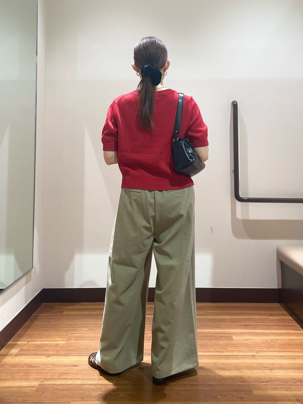 レッド系のニット/セーター、ブラック系のショルダーバッグ、ブラック系のサンダルを着用したレディースの夏コーディネートの3枚目の写真