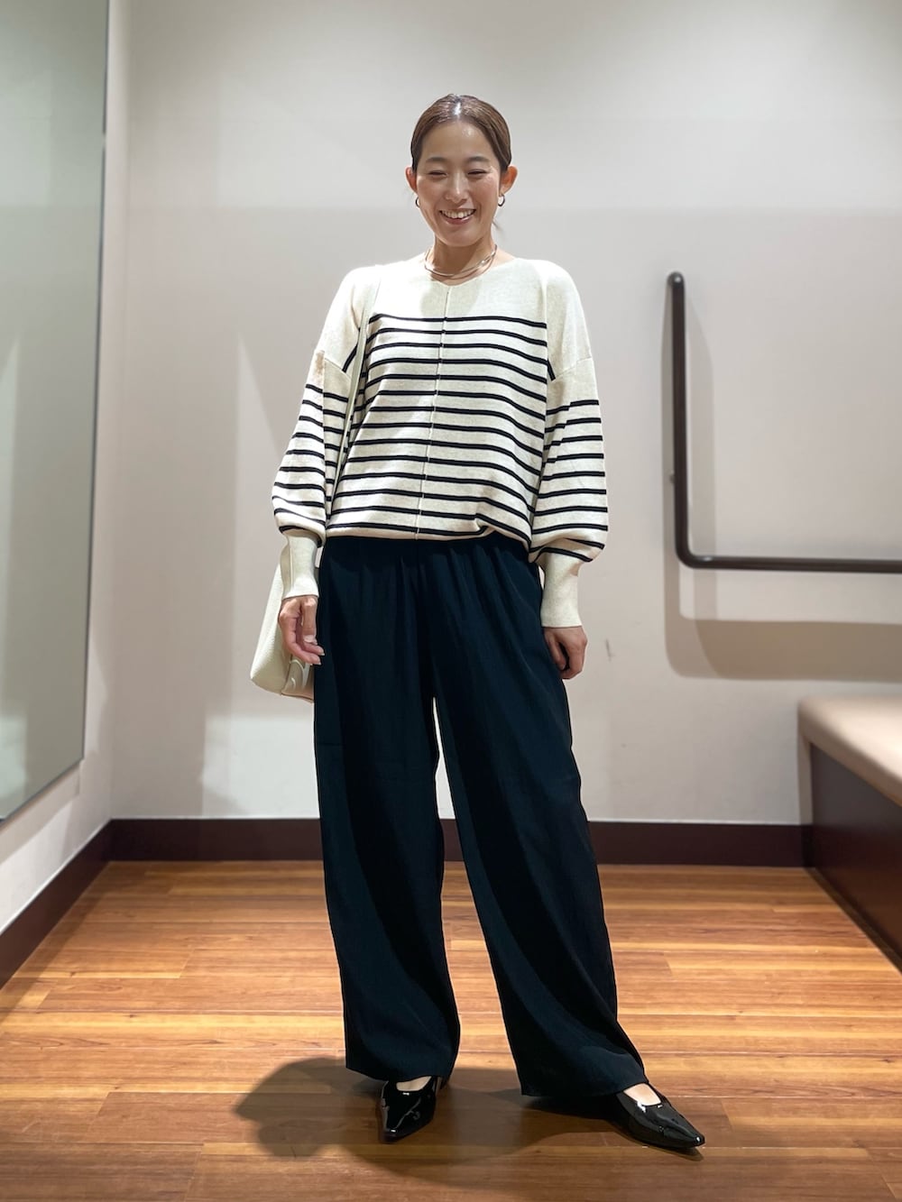ブラック系のパンプス、ホワイト系のショルダーバッグ、ホワイト系のニット/セーターを着用したレディースの秋コーディネートの2枚目の写真