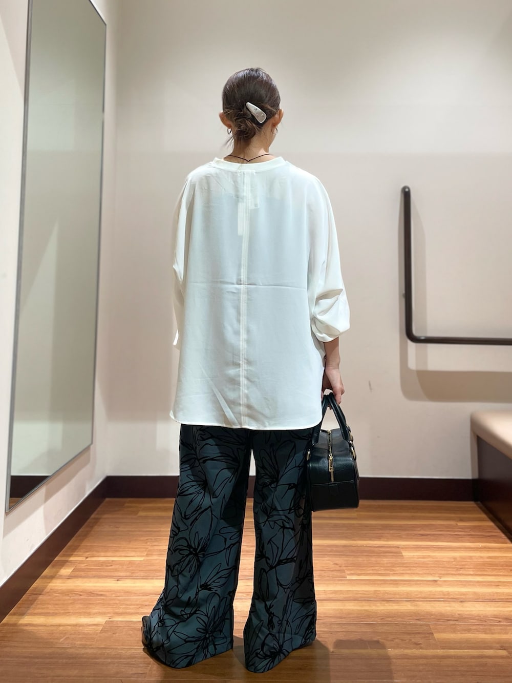 ブラック系のハンドバッグ、ホワイト系のシャツ/ブラウス、ブラック系のパンプスを着用したレディースの秋コーディネートの3枚目の写真