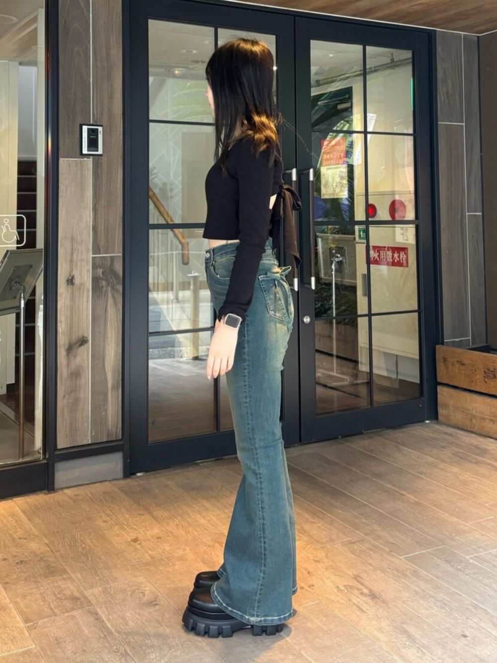 ブルー系のデニムパンツ、ブラック系のブーツ、ブラック系のTシャツ/カットソーを着用したレディースの春コーディネートの2枚目の写真