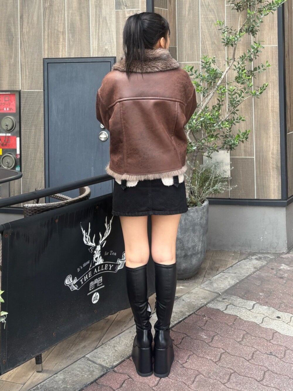 ホワイト系のTシャツ/カットソー、ブラック系のブーツ、ブラック系のデニムスカートを着用したレディースの秋コーディネートの3枚目の写真