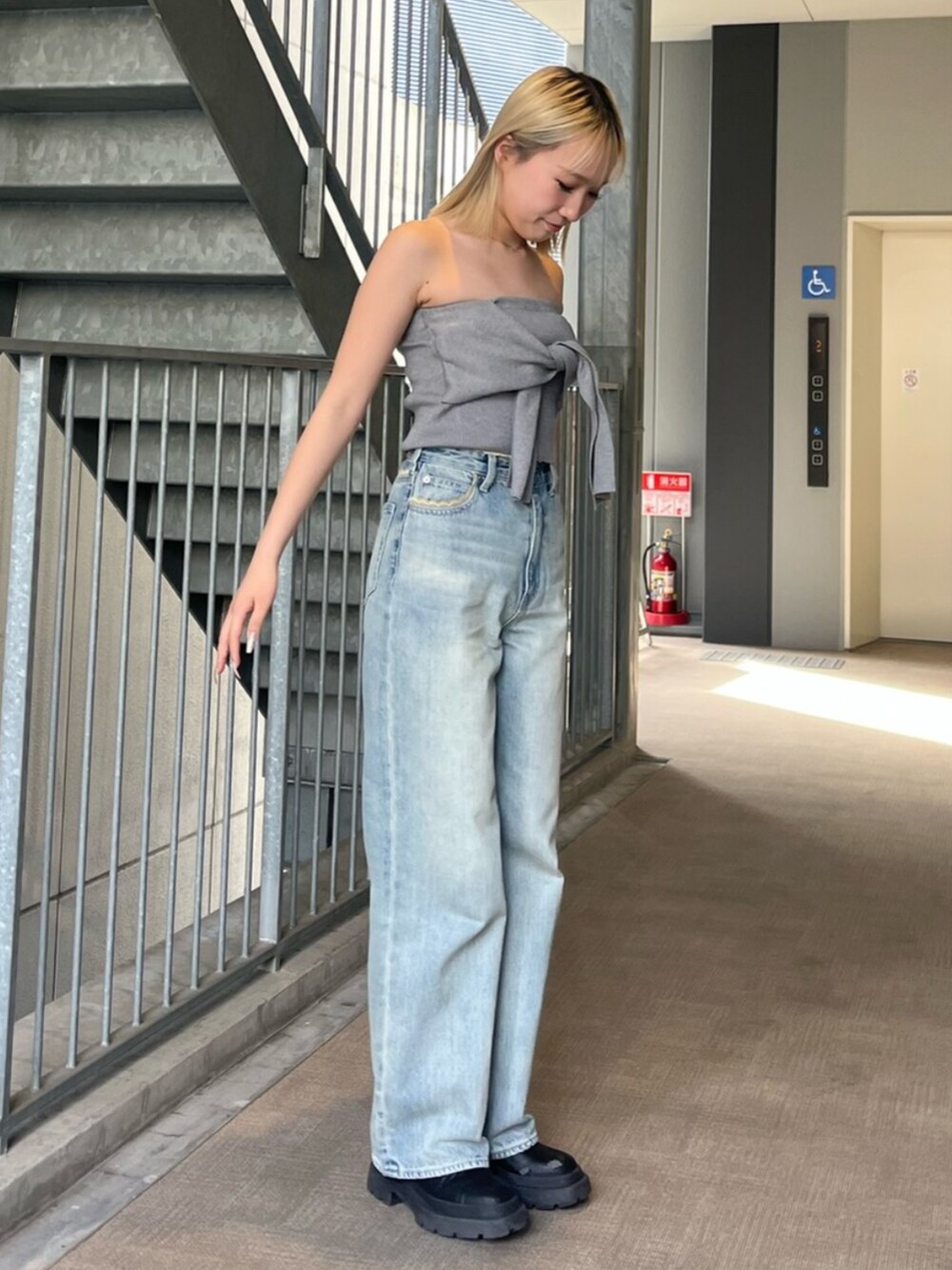 ブラック系のブーツ、グレー系のキャミソール、ブルー系のデニムパンツを着用したレディースの春コーディネートの2枚目の写真