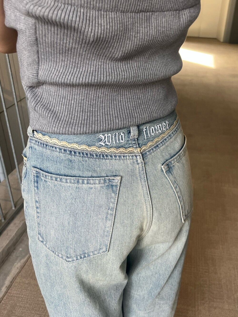 ブラック系のブーツ、グレー系のキャミソール、ブルー系のデニムパンツを着用したレディースの春コーディネートの6枚目の写真