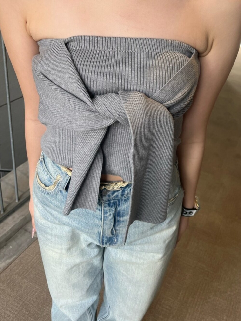 ブラック系のブーツ、グレー系のキャミソール、ブルー系のデニムパンツを着用したレディースの春コーディネートの5枚目の写真