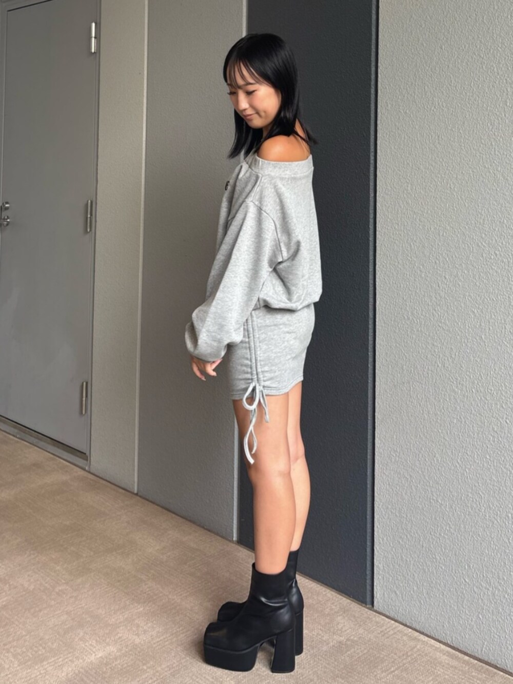 ブラック系のブーツ、グレー系のパーカー、グレー系のスカートを着用したレディースの秋コーディネートの2枚目の写真