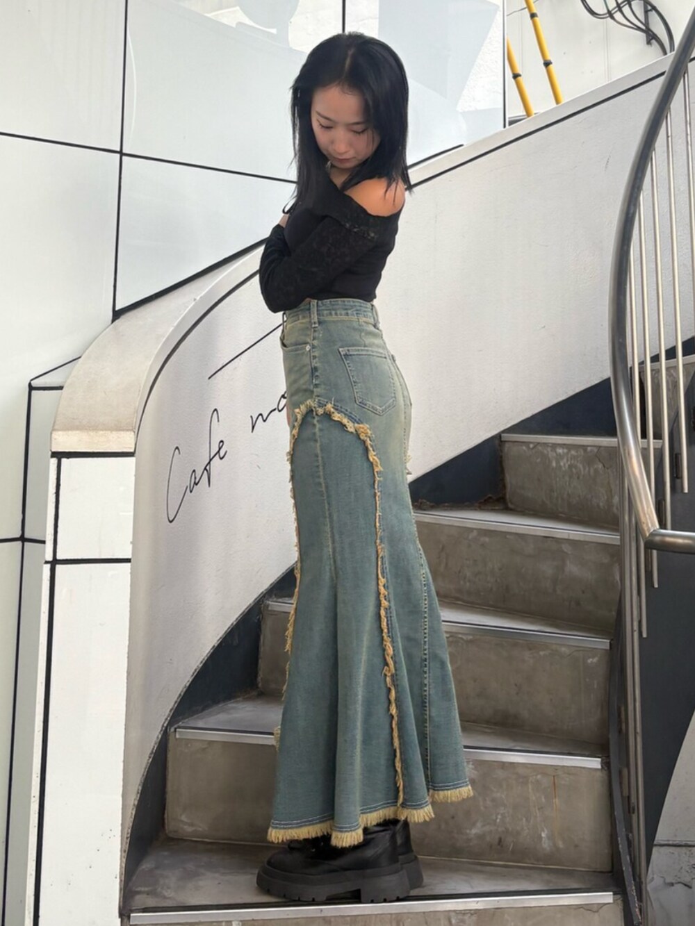 ブラック系のブーツ、ブルー系のデニムスカート、ブラック系のTシャツ/カットソーを着用したレディースの夏コーディネートの2枚目の写真