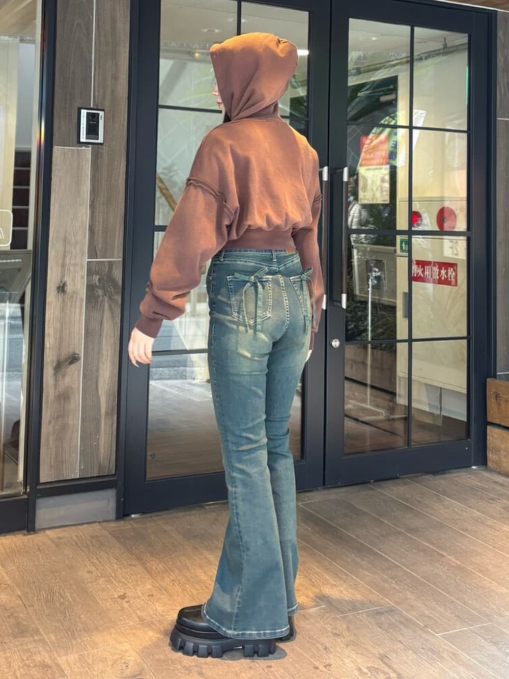 ブラウン系のパーカー、ブルー系のデニムパンツ、ブラック系のブーツを着用したレディースの春コーディネートの2枚目の写真