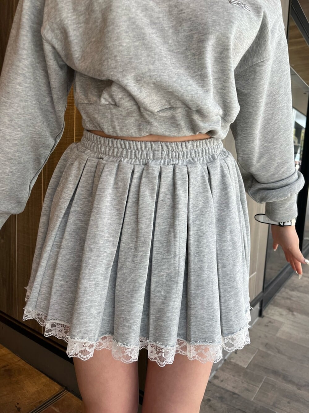 グレー系のスウェット、グレー系のスカート、ブラック系のブーツを着用したレディースの春コーディネートの6枚目の写真