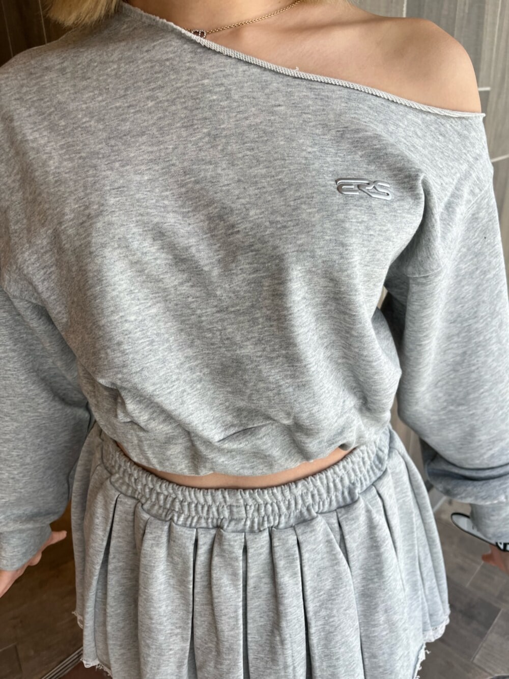 グレー系のスウェット、グレー系のスカート、ブラック系のブーツを着用したレディースの春コーディネートの5枚目の写真