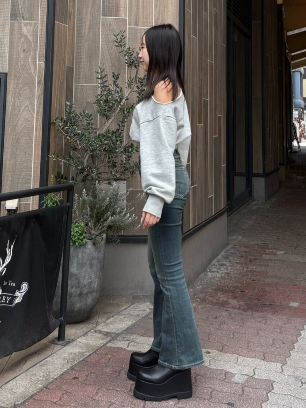 ブルー系のデニムパンツ、ブラック系のブーツ、グレー系のスウェットを着用したレディースの冬コーディネートの2枚目の写真