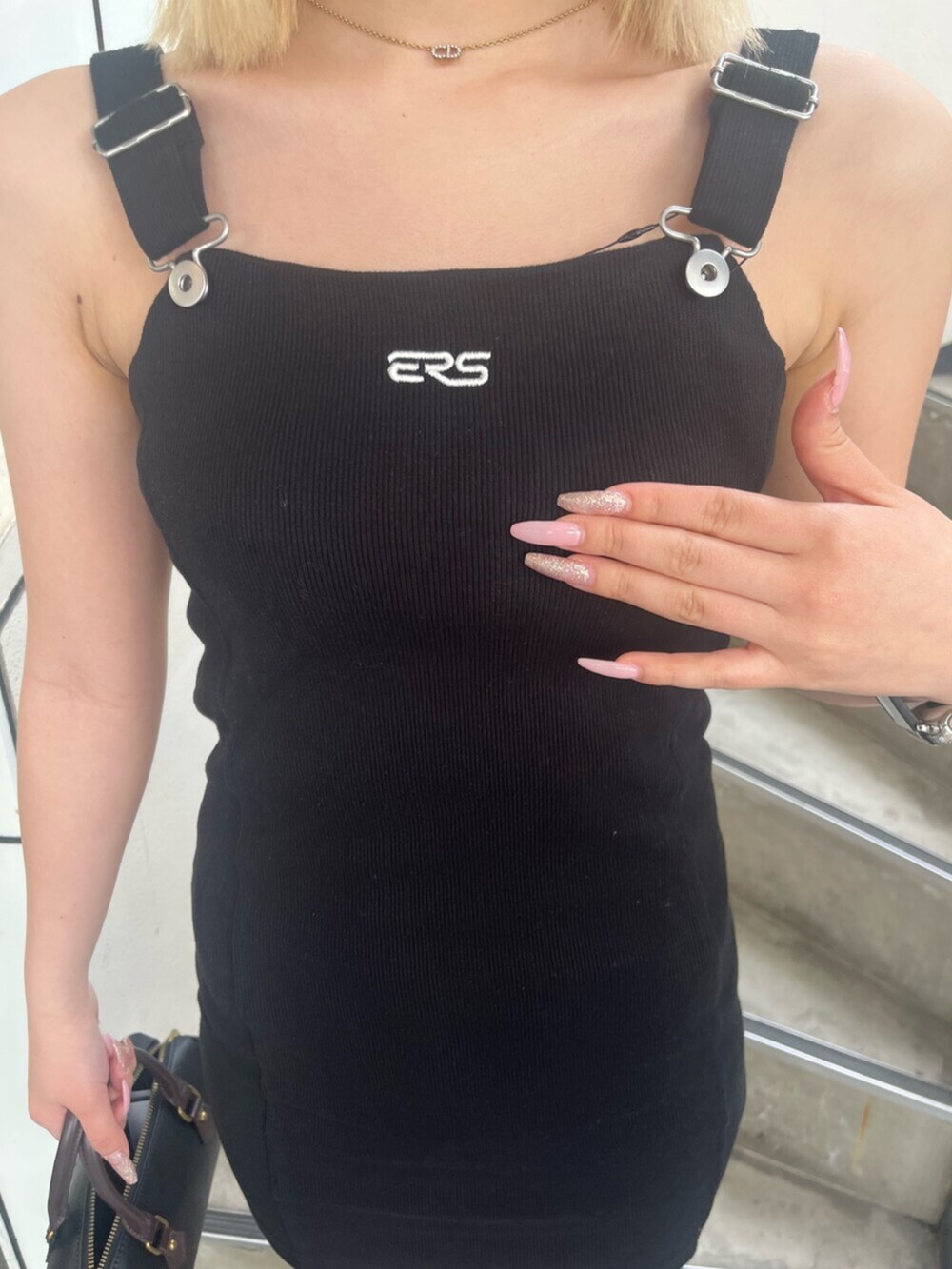 ブラック系のブーツ、ブラック系のジャンパースカート、ブラック系のショルダーバッグを着用したレディースの春コーディネートの5枚目の写真