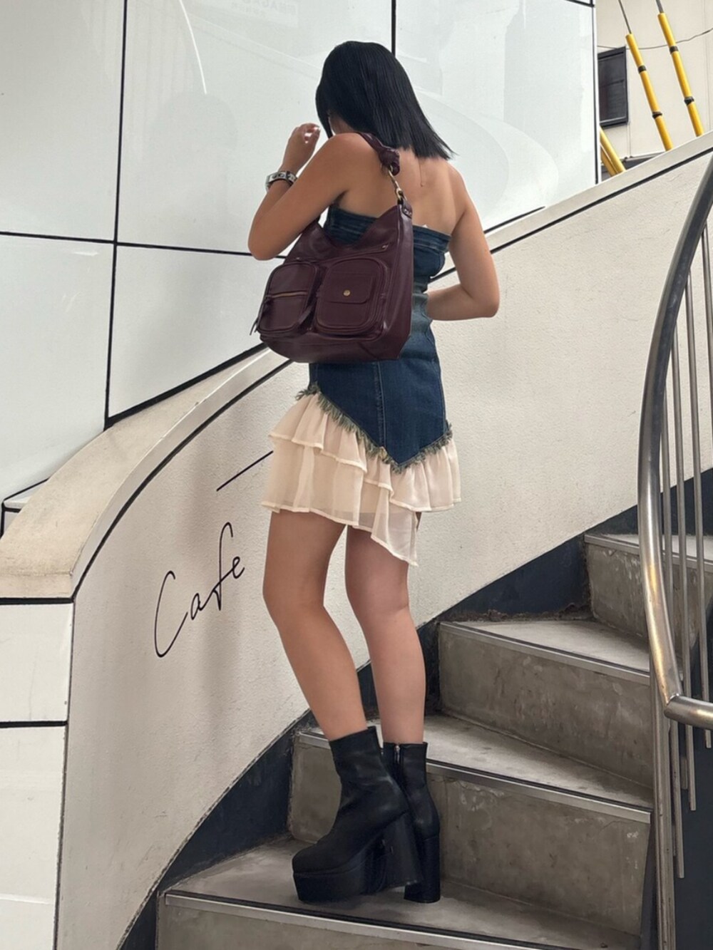 ブラック系のブーツ、ブルー系のワンピース、レッド系のハンドバッグを着用したレディースの夏コーディネートの2枚目の写真