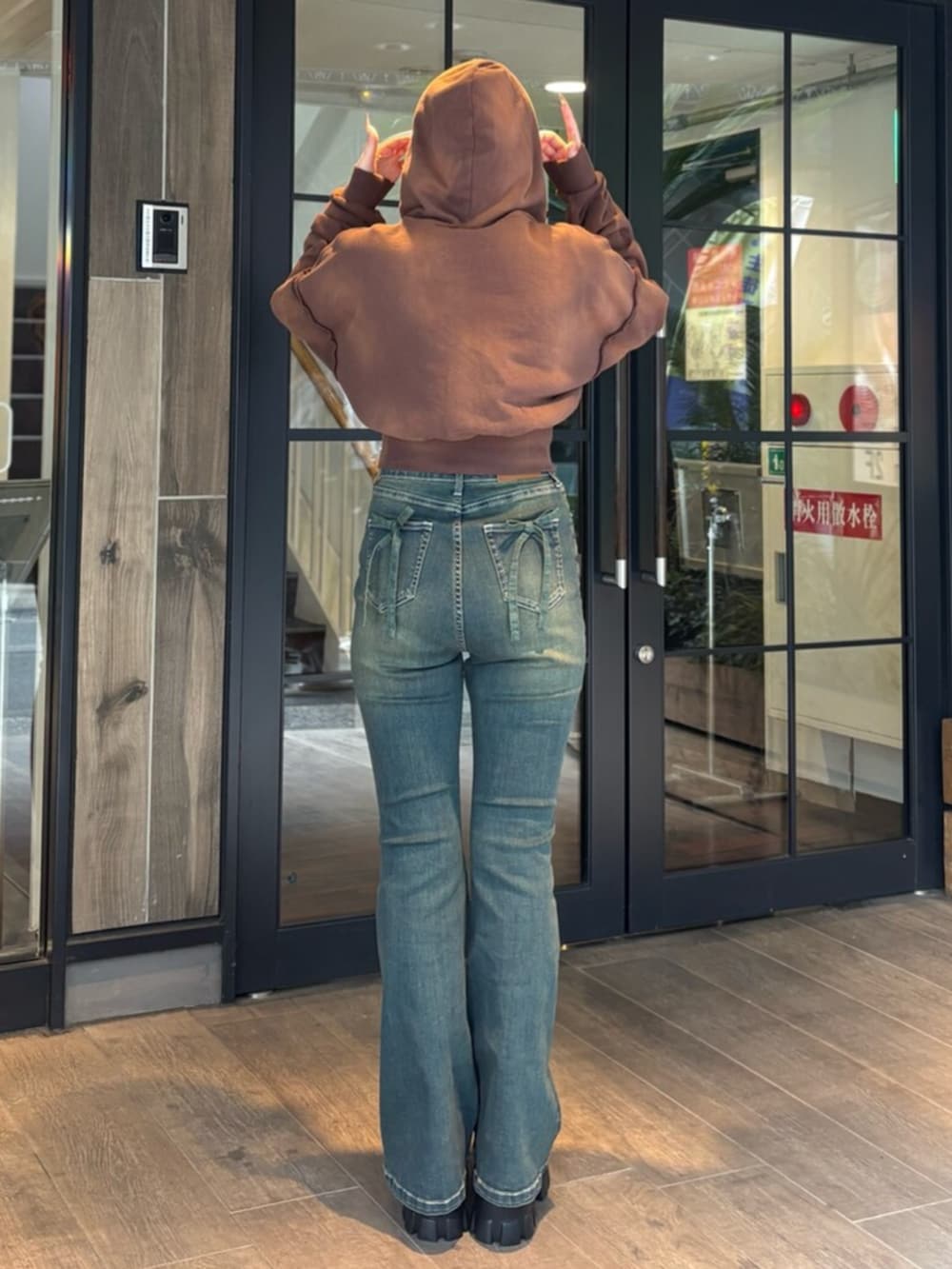 ブラウン系のパーカー、ブルー系のデニムパンツ、ブラック系のブーツを着用したレディースの春コーディネートの3枚目の写真