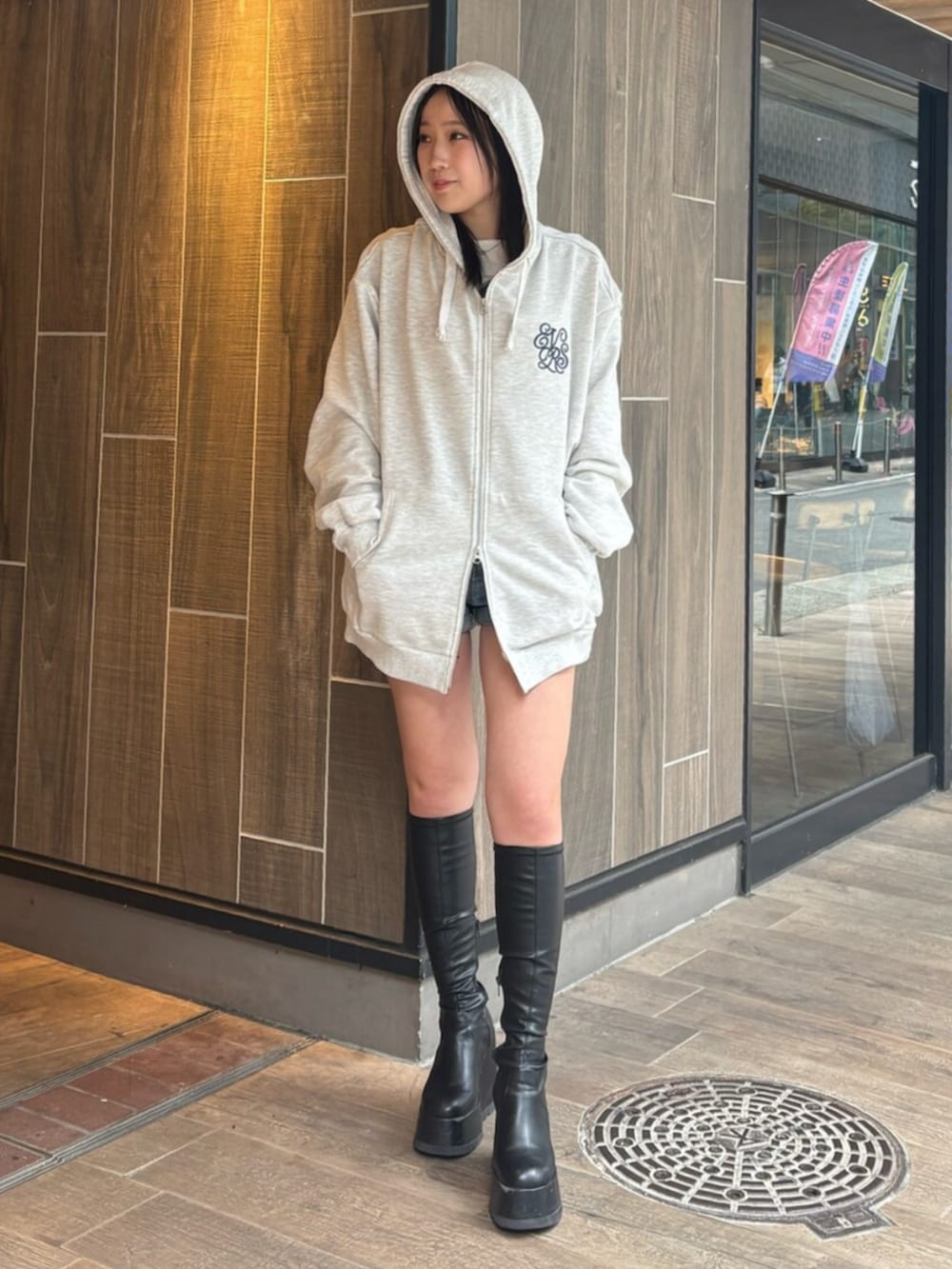 ブラック系のブーツ、ブルー系のデニムパンツ、グレー系のパーカーを着用したレディースの春コーディネートの2枚目の写真