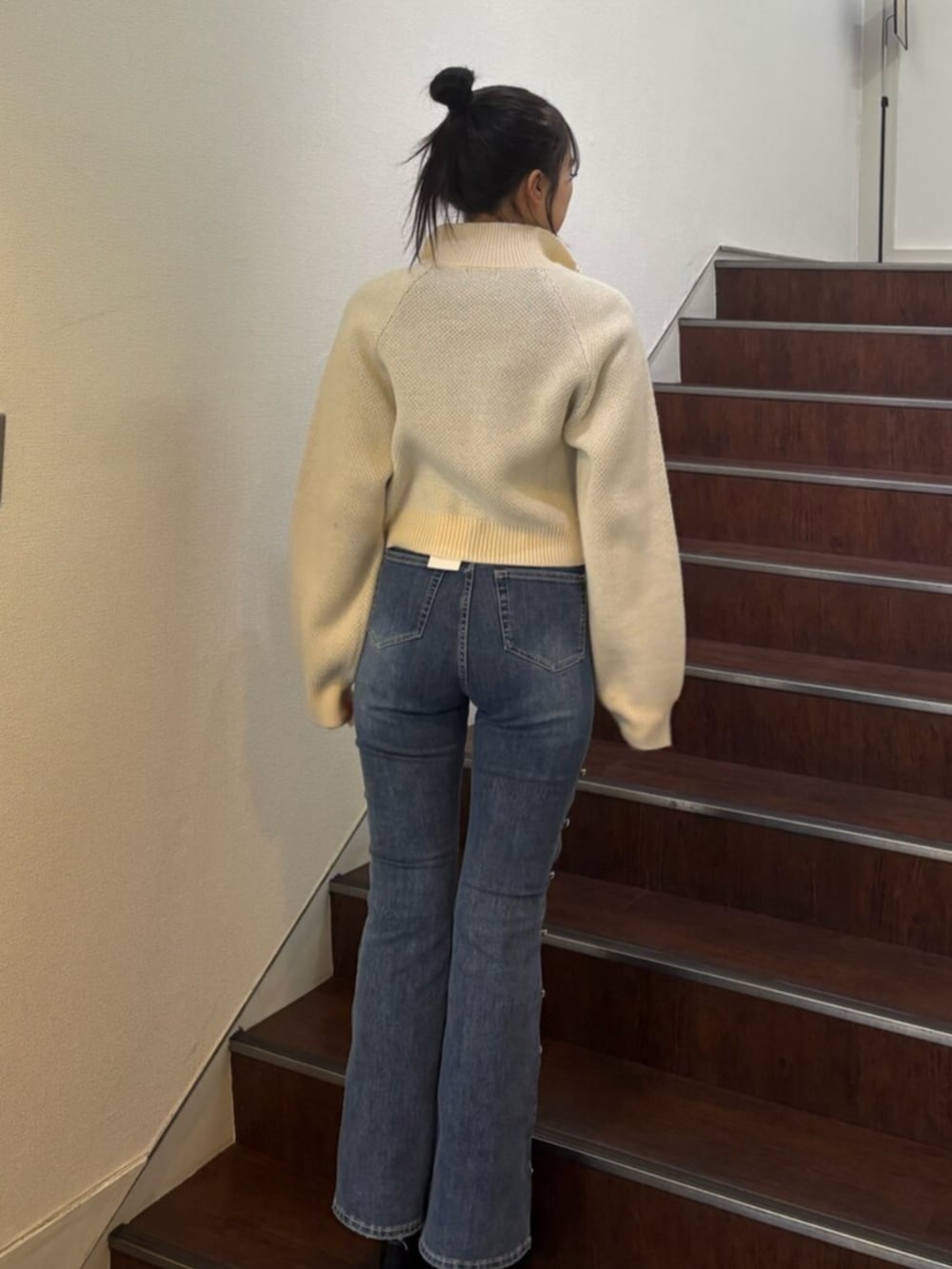 ホワイト系のニット/セーター、ブルー系のデニムパンツ、ブラック系のブーツを着用したレディースの冬コーディネートの3枚目の写真