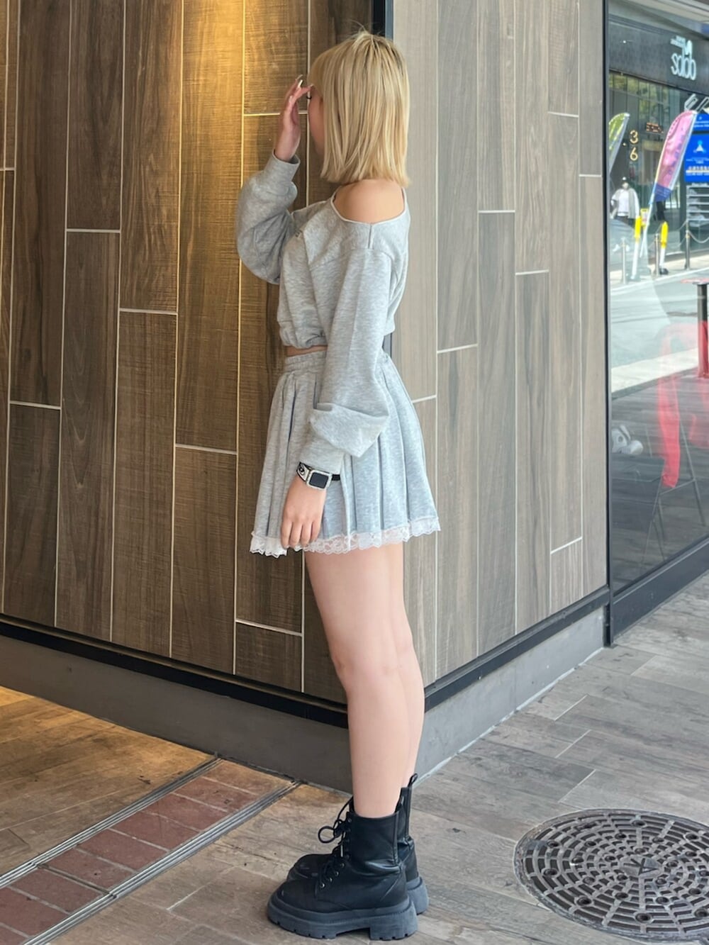 グレー系のスウェット、グレー系のスカート、ブラック系のブーツを着用したレディースの春コーディネートの2枚目の写真