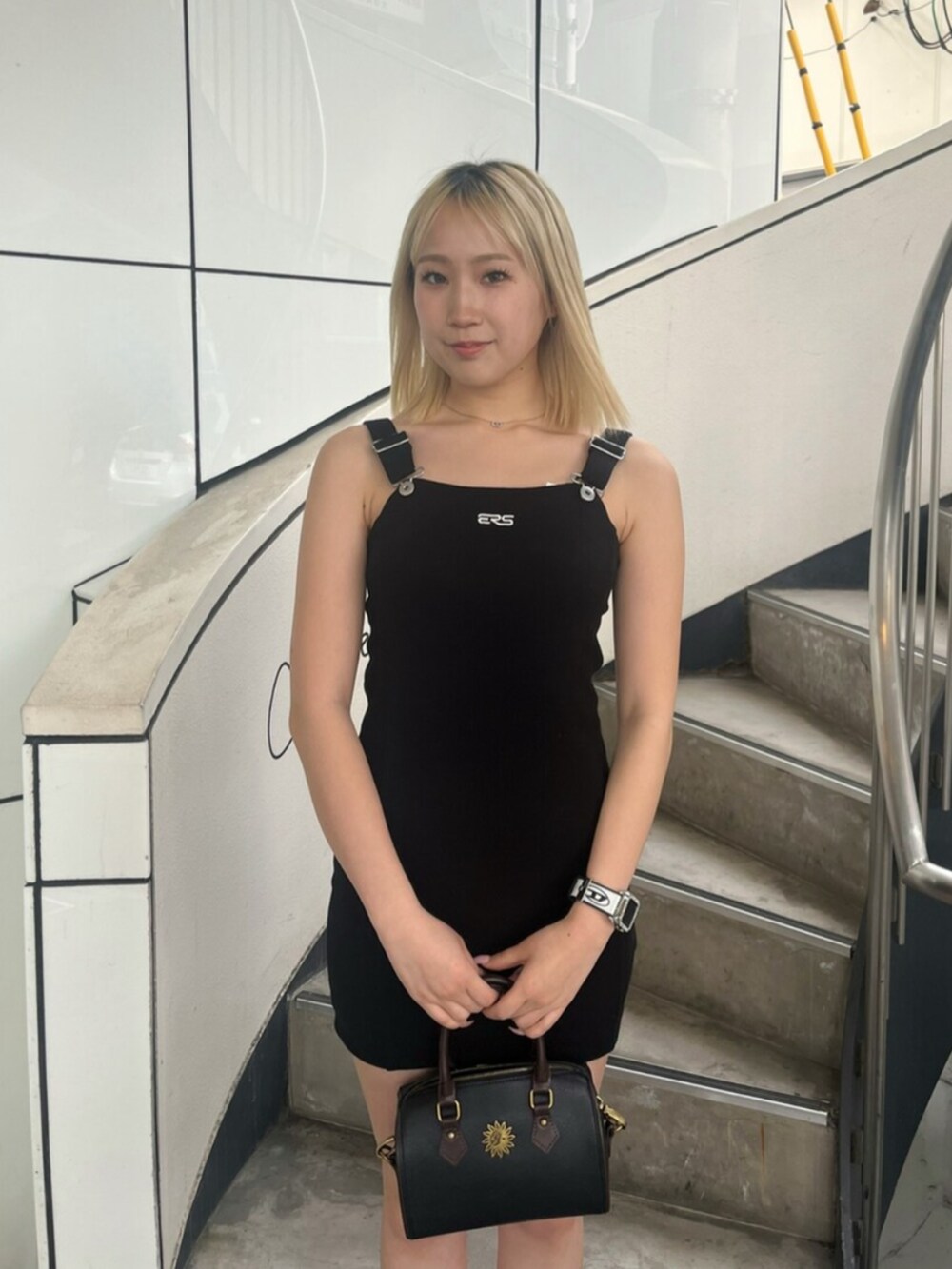 ブラック系のブーツ、ブラック系のジャンパースカート、ブラック系のショルダーバッグを着用したレディースの春コーディネートの4枚目の写真