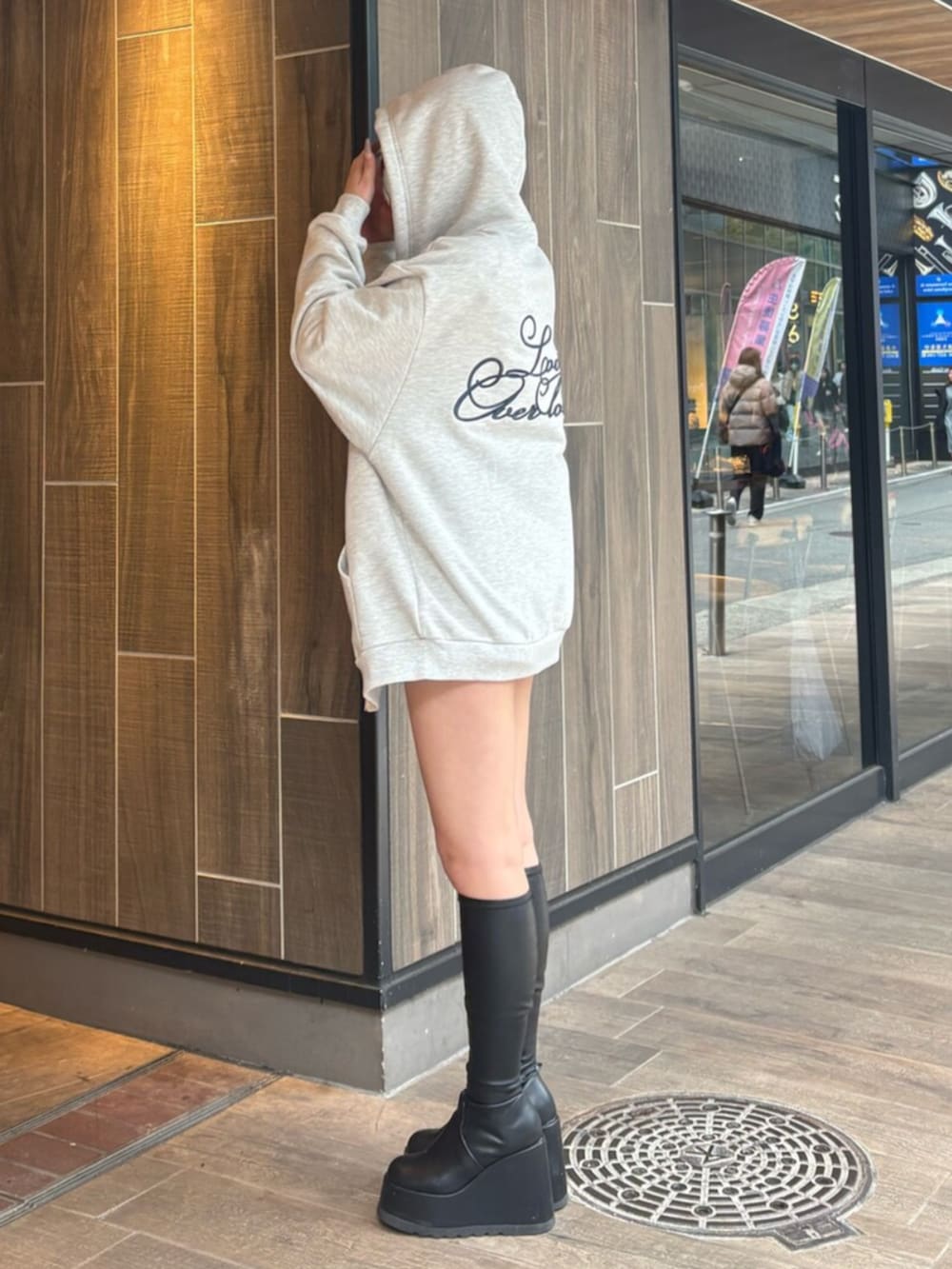 ブラック系のブーツ、ブルー系のデニムパンツ、グレー系のパーカーを着用したレディースの春コーディネートの3枚目の写真