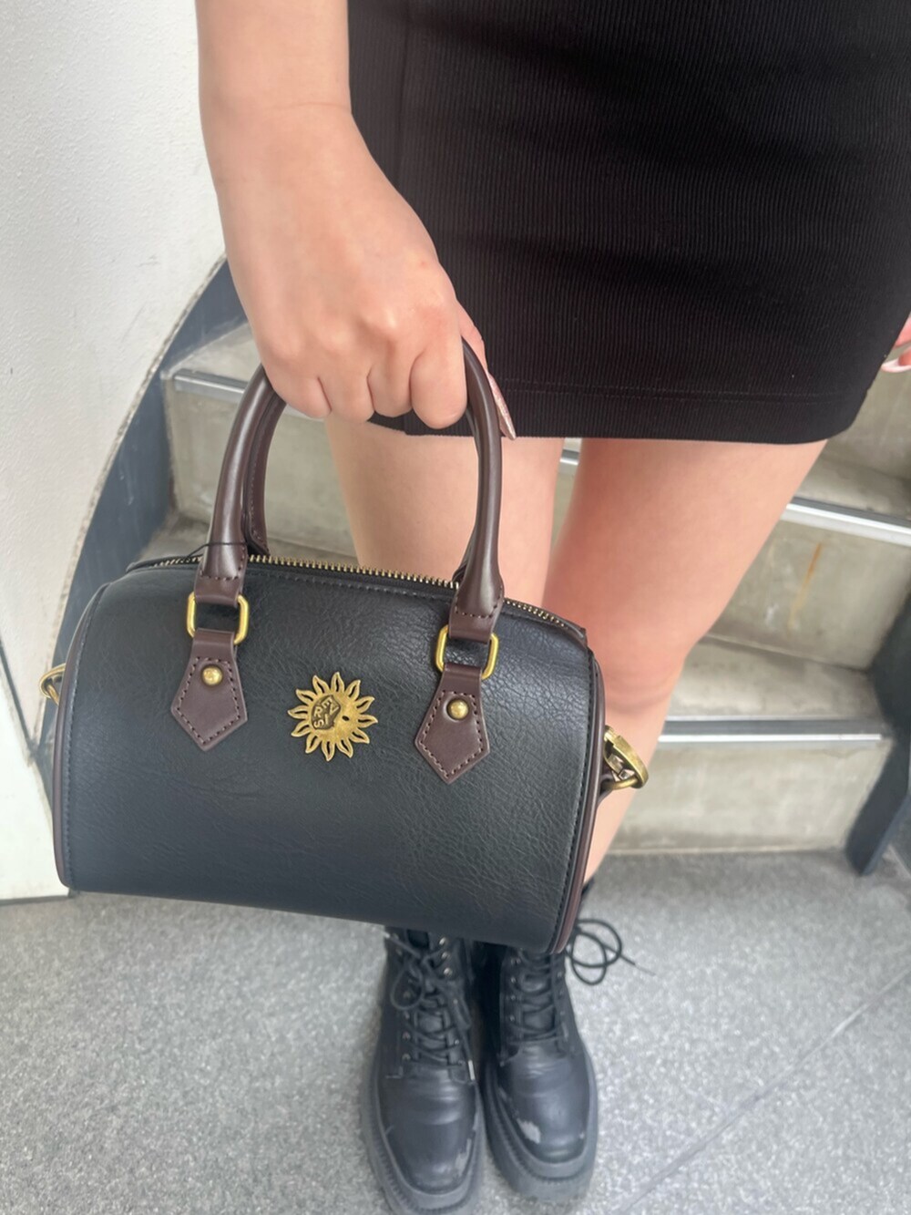 ブラック系のブーツ、ブラック系のジャンパースカート、ブラック系のショルダーバッグを着用したレディースの春コーディネートの6枚目の写真