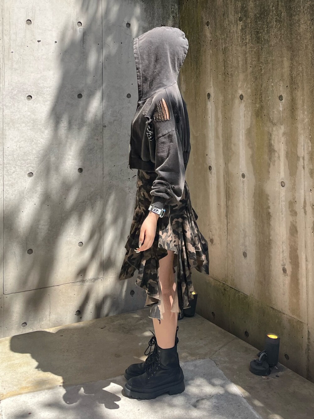 ブラック系のパーカー、ブラック系のブーツ、グリーン系のワンピースを着用したレディースの春コーディネートの2枚目の写真