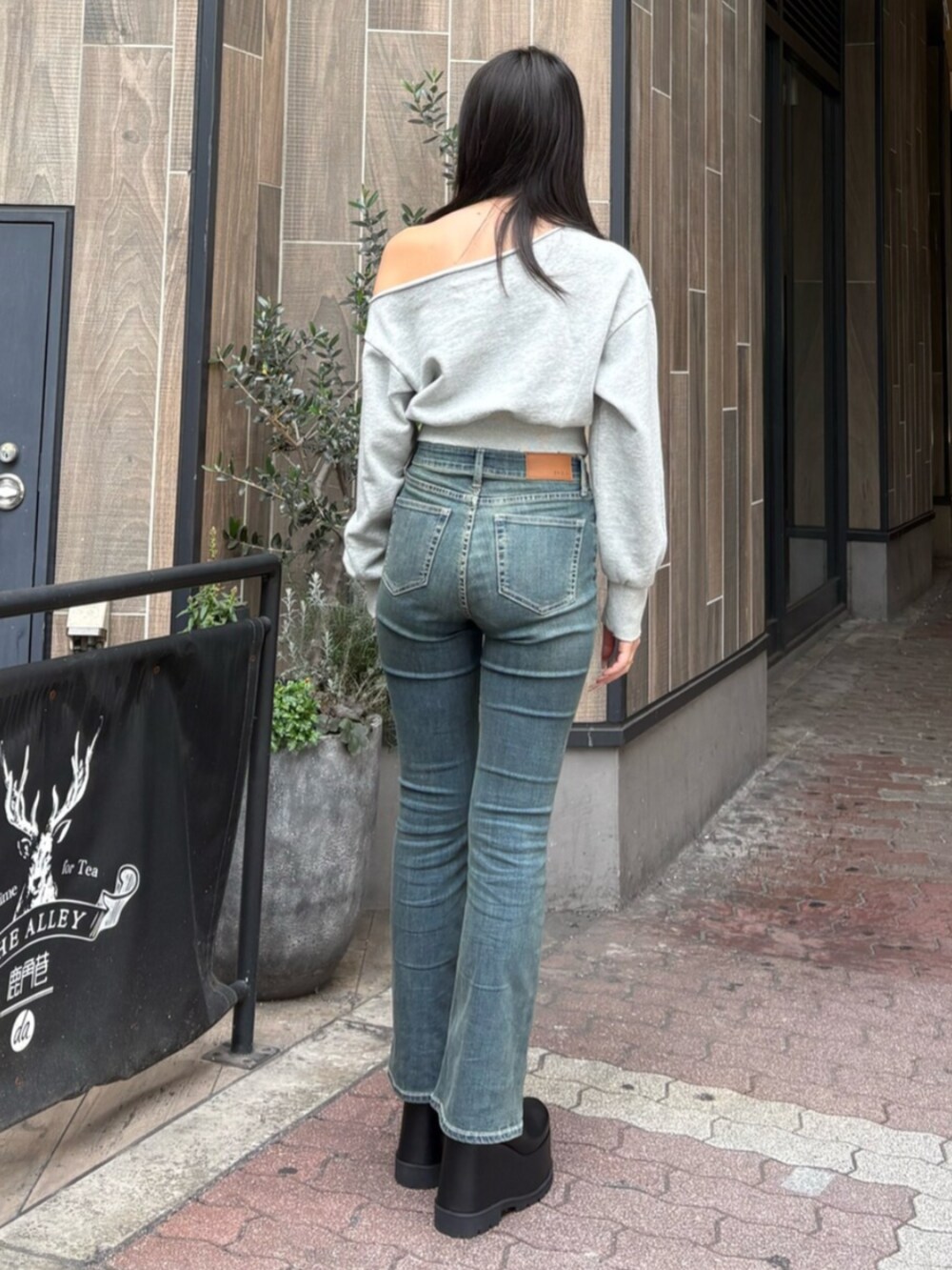 ブルー系のデニムパンツ、ブラック系のブーツ、グレー系のスウェットを着用したレディースの冬コーディネートの3枚目の写真