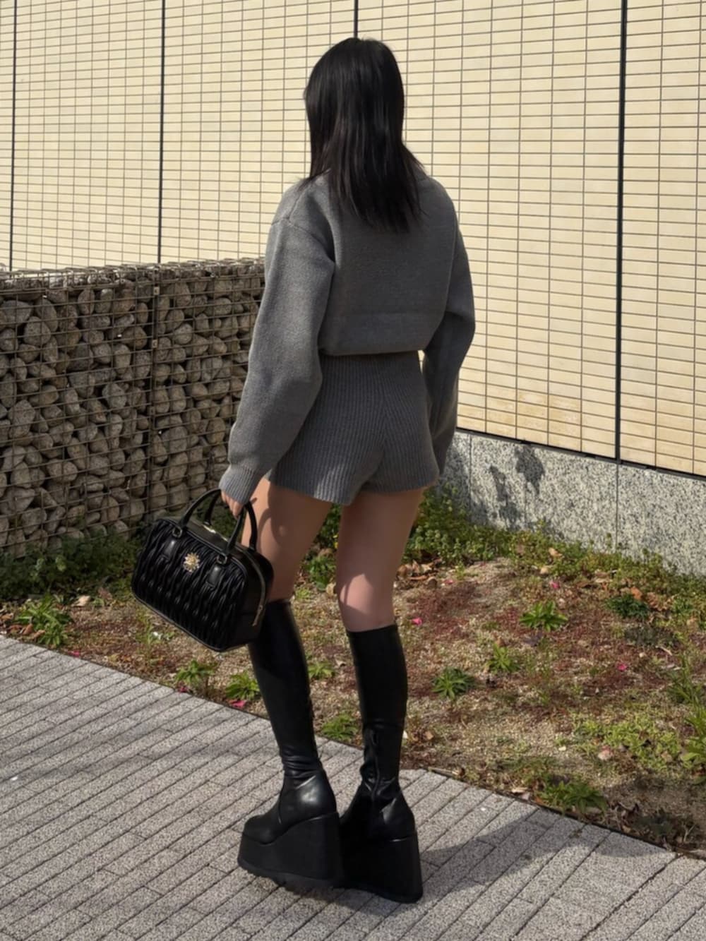 ブラック系のブーツ、グレー系のつなぎ/オールインワン、ブラック系のハンドバッグを着用したレディースの冬コーディネートの2枚目の写真