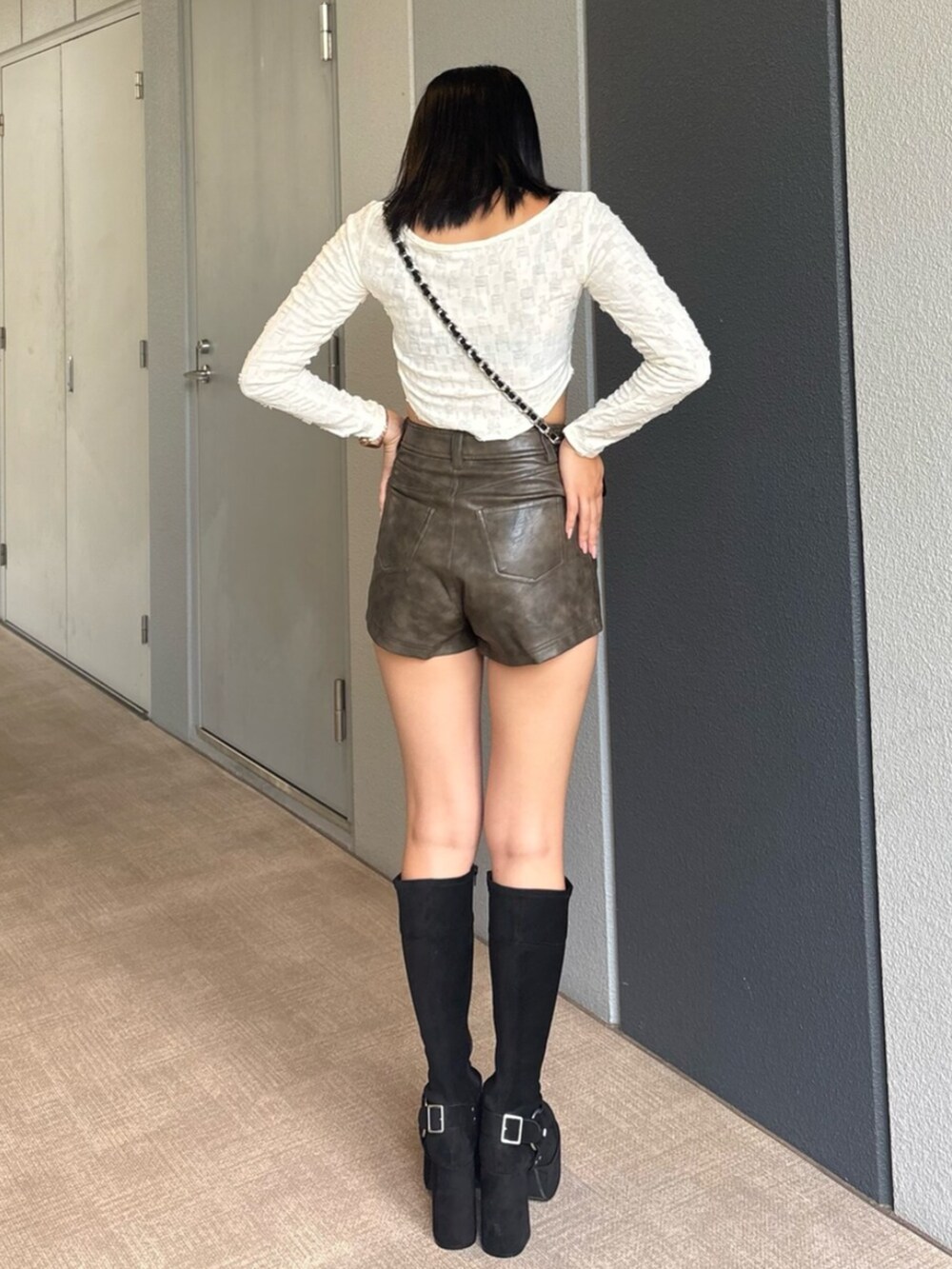 ブラック系のハンドバッグ、ブラック系のブーツ、ホワイト系のTシャツ/カットソーを着用したレディースの秋コーディネートの3枚目の写真