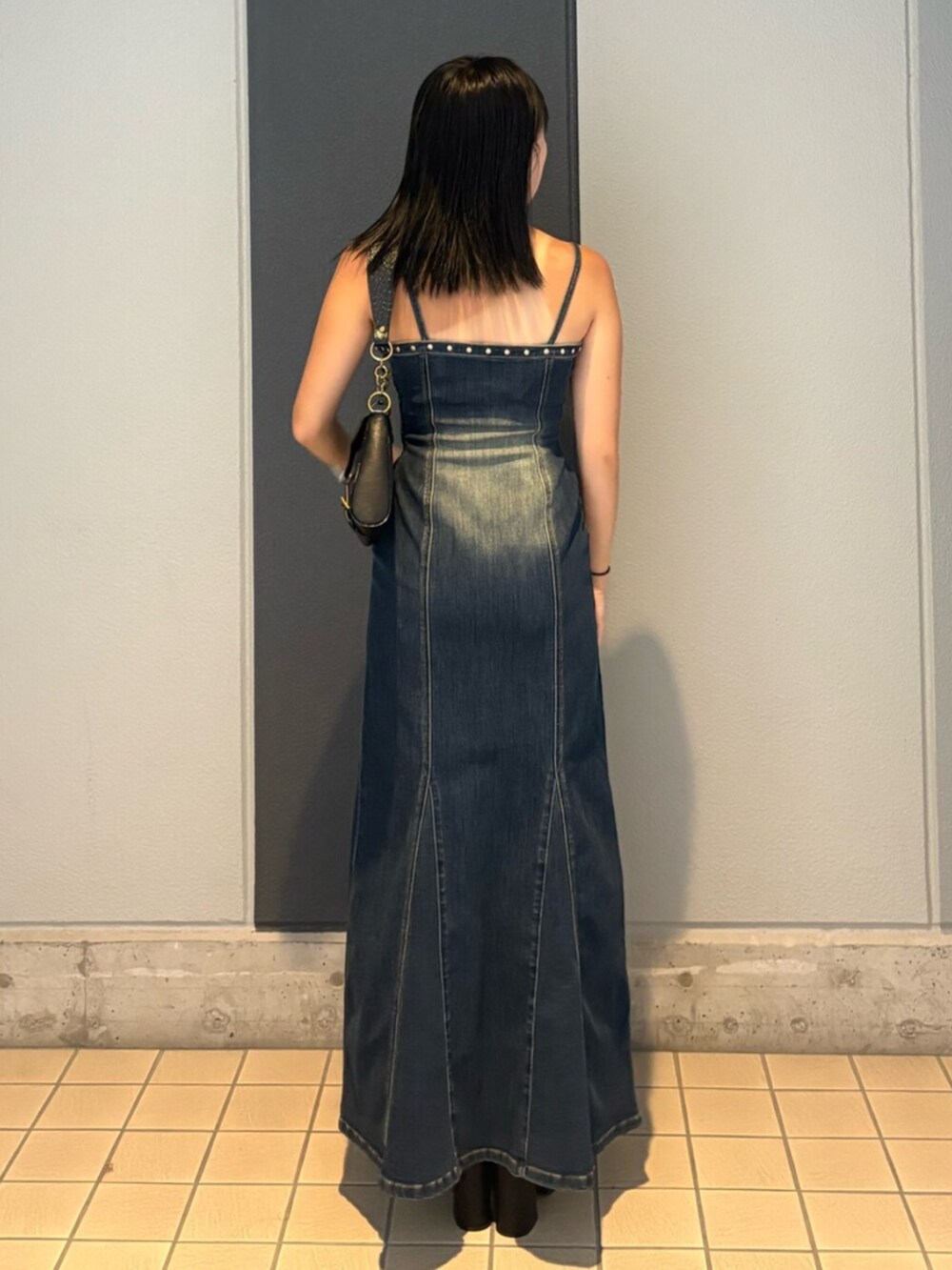 ブルー系のワンピース、ブラック系のハンドバッグ、ブラック系のブーツを着用したレディースの夏コーディネートの3枚目の写真