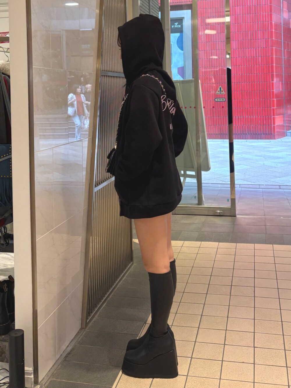 ブラック系のハンドバッグ、ブラック系のブーツ、ブラック系のパーカーを着用したレディースの秋コーディネートの2枚目の写真