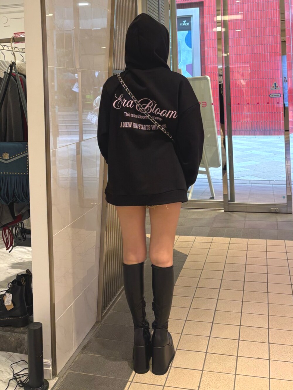 ブラック系のハンドバッグ、ブラック系のブーツ、ブラック系のパーカーを着用したレディースの秋コーディネートの3枚目の写真