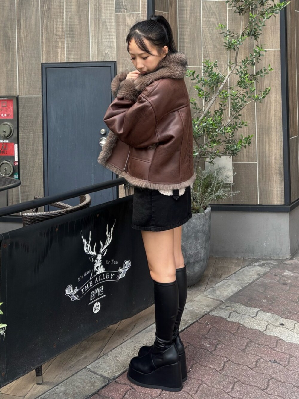 ホワイト系のTシャツ/カットソー、ブラック系のブーツ、ブラック系のデニムスカートを着用したレディースの秋コーディネートの2枚目の写真