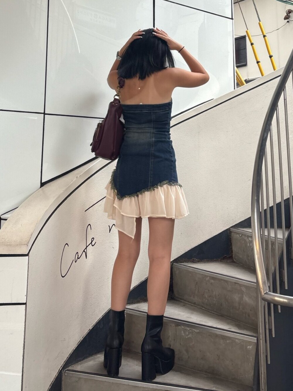 ブラック系のブーツ、ブルー系のワンピース、レッド系のハンドバッグを着用したレディースの夏コーディネートの3枚目の写真