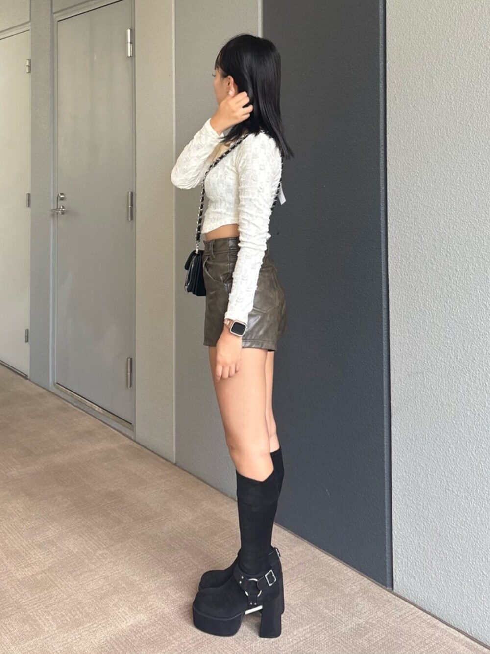 ブラック系のハンドバッグ、ブラック系のブーツ、ホワイト系のTシャツ/カットソーを着用したレディースの秋コーディネートの2枚目の写真