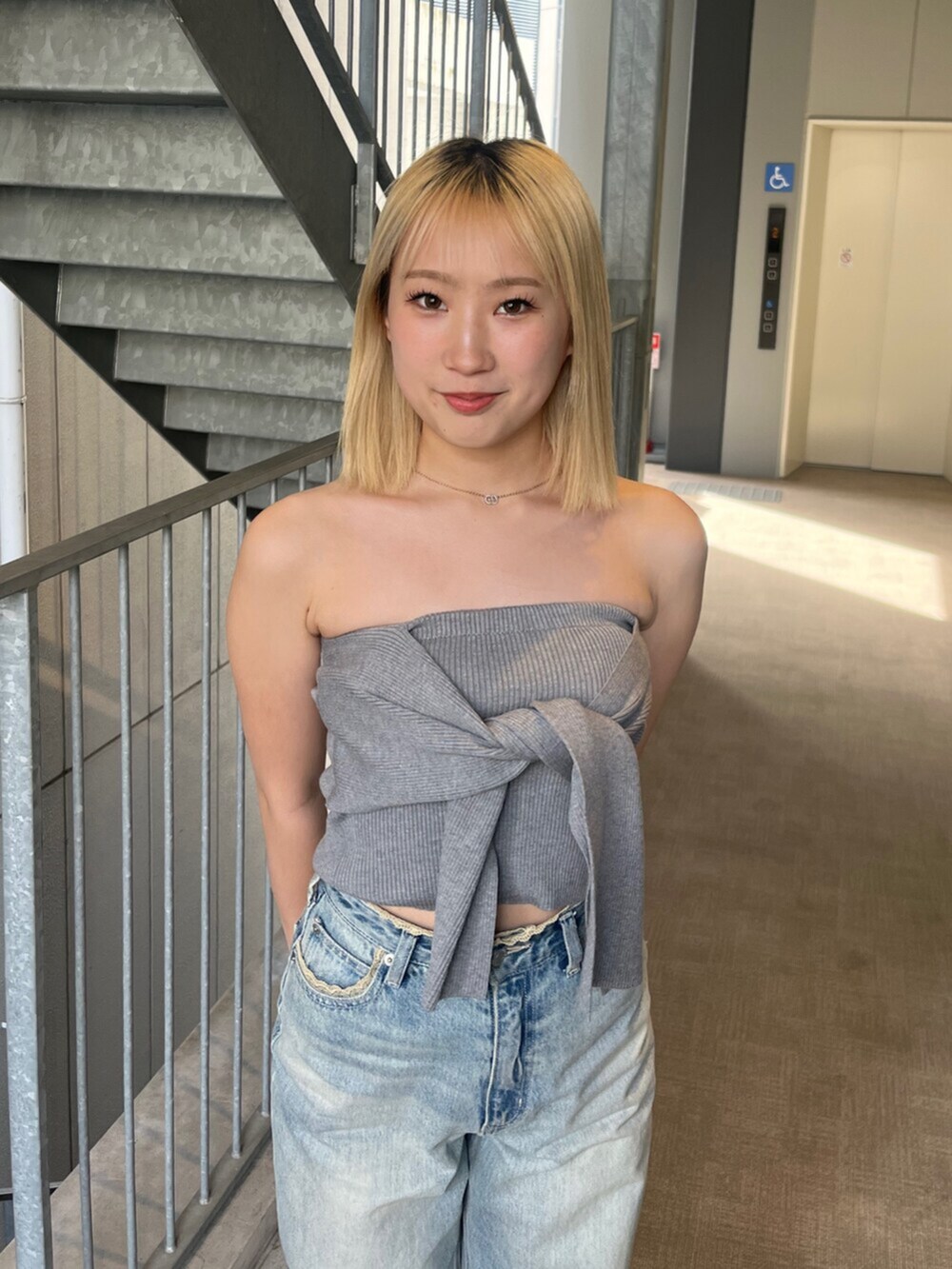 ブラック系のブーツ、グレー系のキャミソール、ブルー系のデニムパンツを着用したレディースの春コーディネートの4枚目の写真