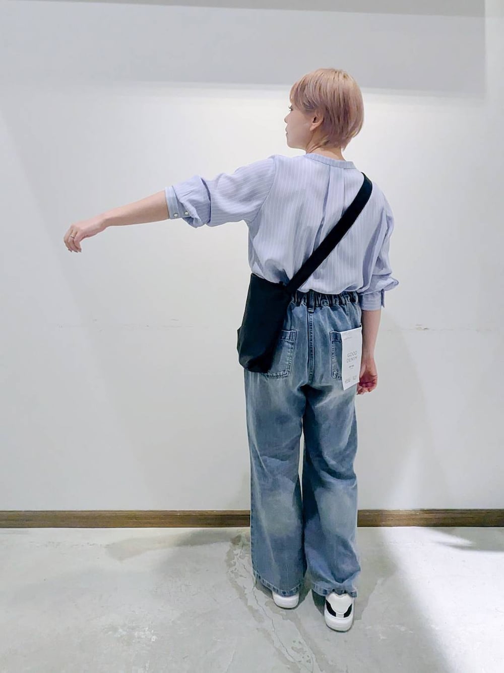 ブラック系のスニーカー、ブラック系のショルダーバッグ、ブルー系のデニムパンツを着用したレディースの秋コーディネートの3枚目の写真