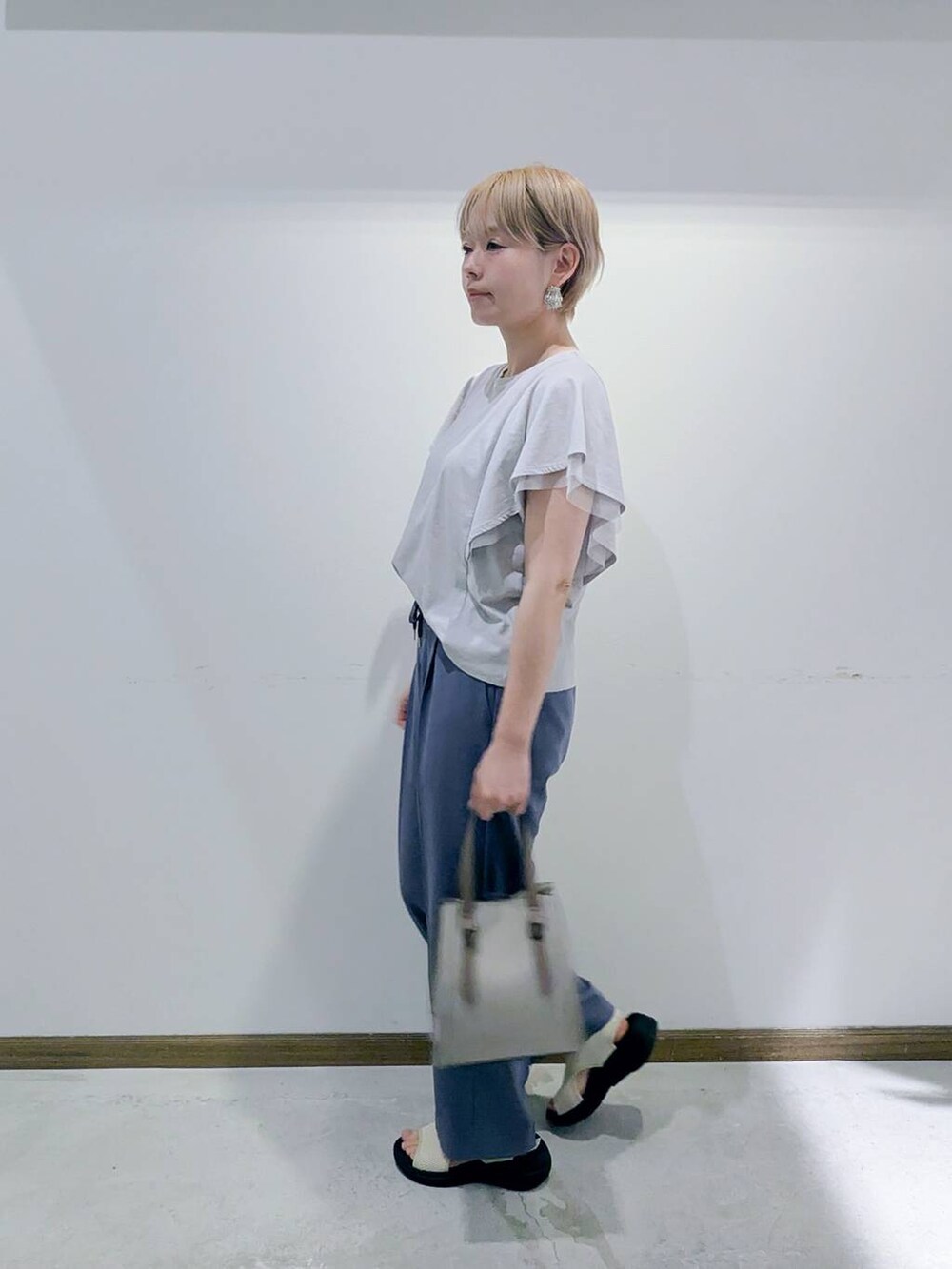 ホワイト系のショルダーバッグ、グレー系のTシャツ/カットソー、ブルー系のスラックスを着用したレディースの秋コーディネートの2枚目の写真