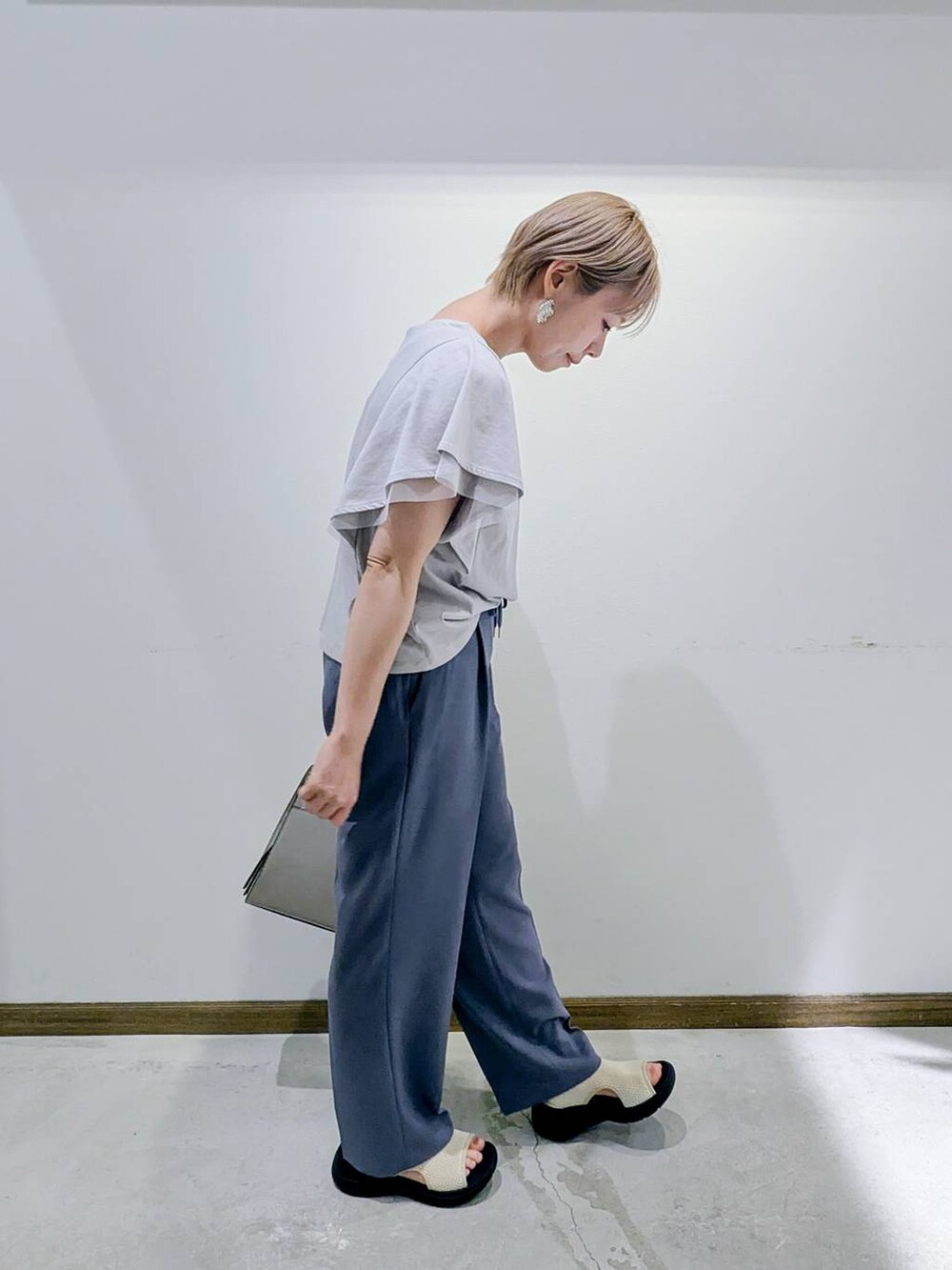 ホワイト系のショルダーバッグ、グレー系のTシャツ/カットソー、ブルー系のスラックスを着用したレディースの秋コーディネートの4枚目の写真