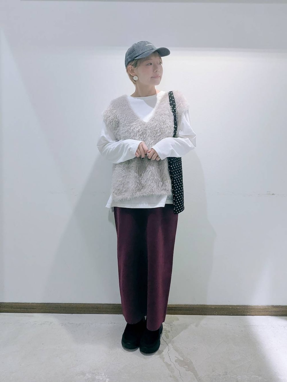 ブラック系のトートバッグ、レッド系のスカート、ブラック系のブーツを着用したレディースの秋コーディネートの5枚目の写真