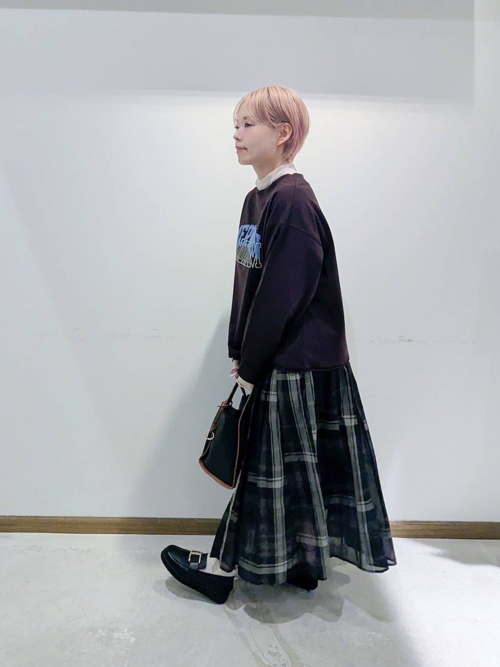 ブラック系のローファー、ブラック系のスカート、ブラック系のトートバッグを着用したレディースの秋コーディネートの4枚目の写真