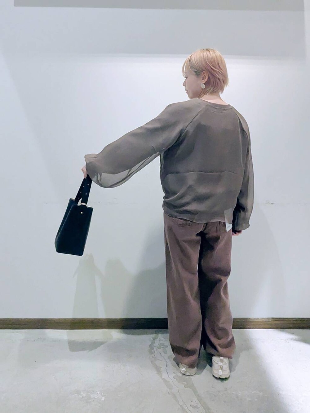 ブラック系のショルダーバッグ、ブラウン系のデニムパンツ、ブラウン系のTシャツ/カットソーを着用したレディースの秋コーディネートの3枚目の写真