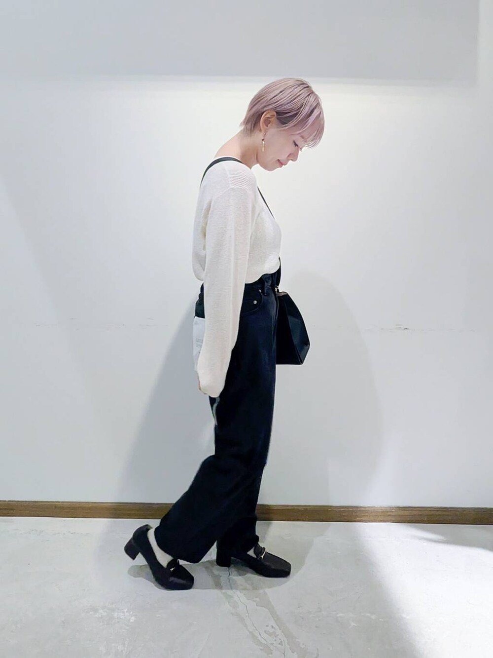 ブラック系のローファー、ブラック系のショルダーバッグ、ブルー系のデニムパンツを着用したレディースの秋コーディネートの2枚目の写真