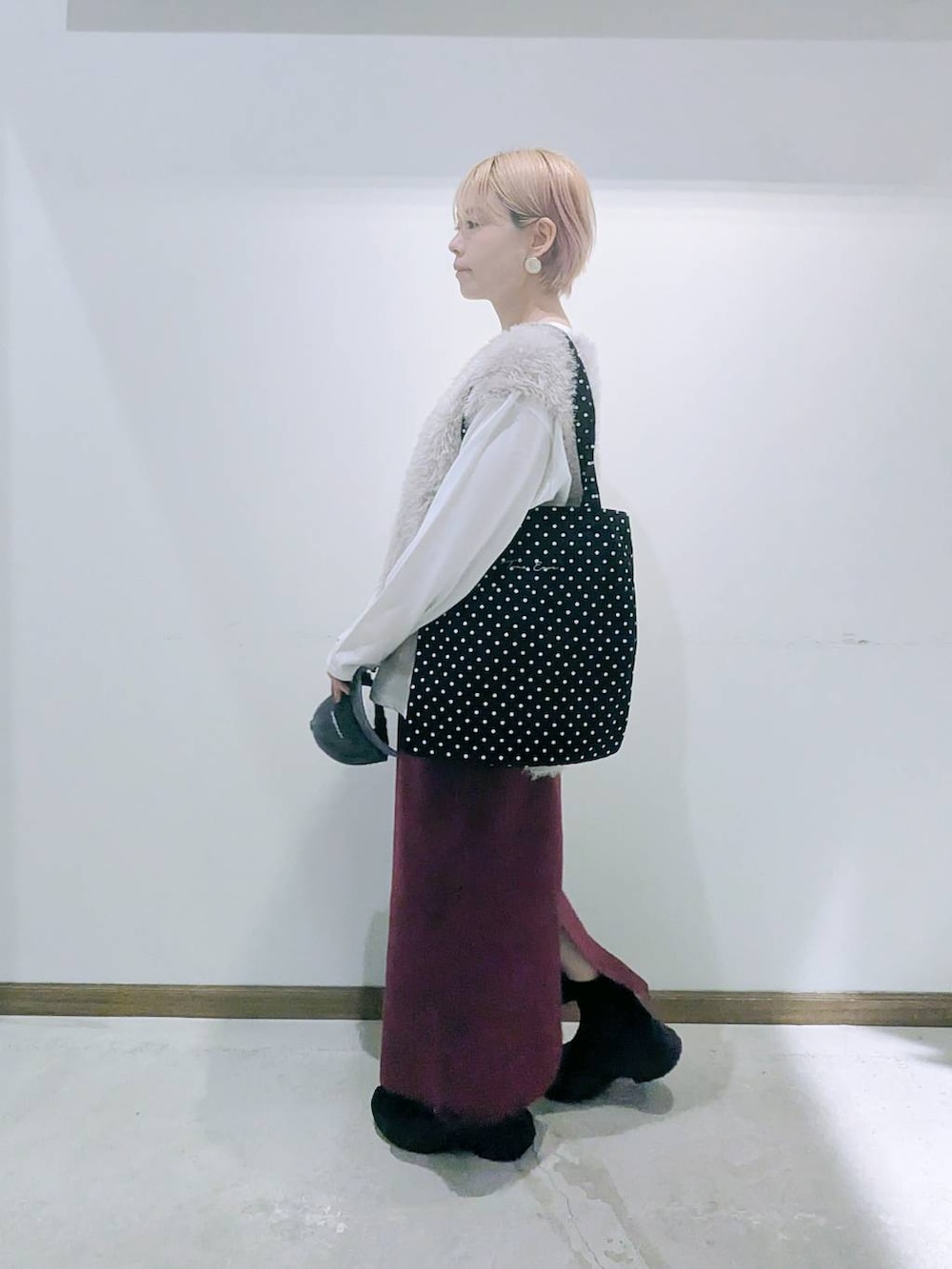 ブラック系のトートバッグ、レッド系のスカート、ブラック系のブーツを着用したレディースの秋コーディネートの4枚目の写真