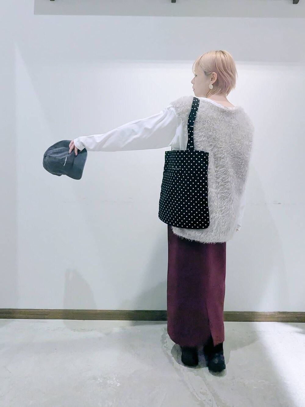 ブラック系のトートバッグ、レッド系のスカート、ブラック系のブーツを着用したレディースの秋コーディネートの3枚目の写真