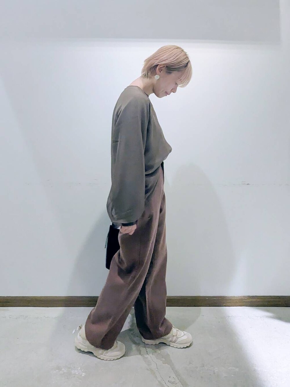 ブラック系のショルダーバッグ、ブラウン系のデニムパンツ、ブラウン系のTシャツ/カットソーを着用したレディースの秋コーディネートの2枚目の写真