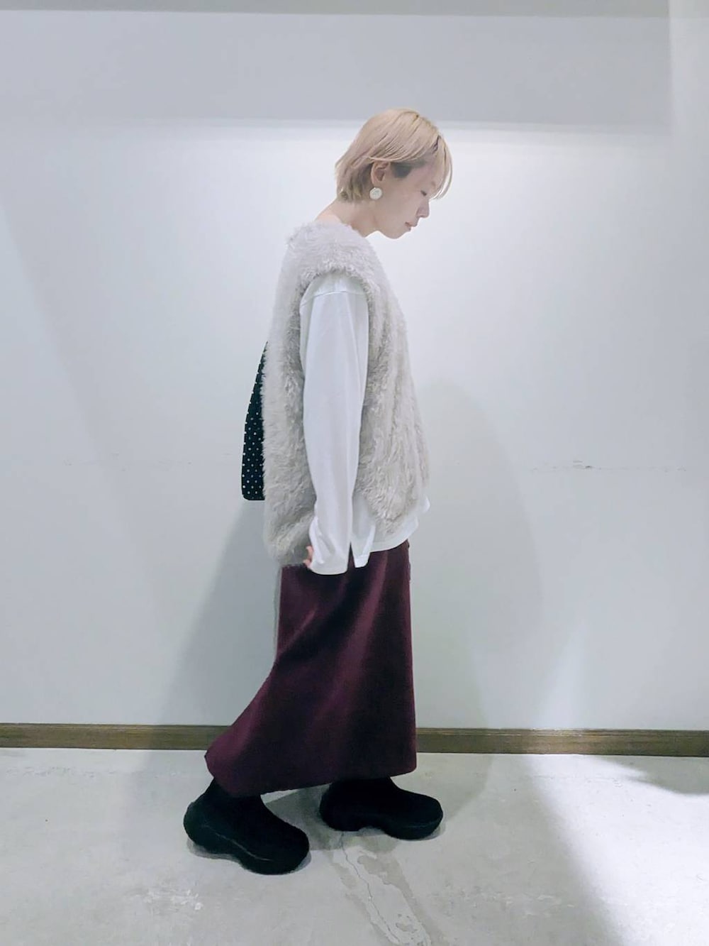 ブラック系のトートバッグ、レッド系のスカート、ブラック系のブーツを着用したレディースの秋コーディネートの2枚目の写真