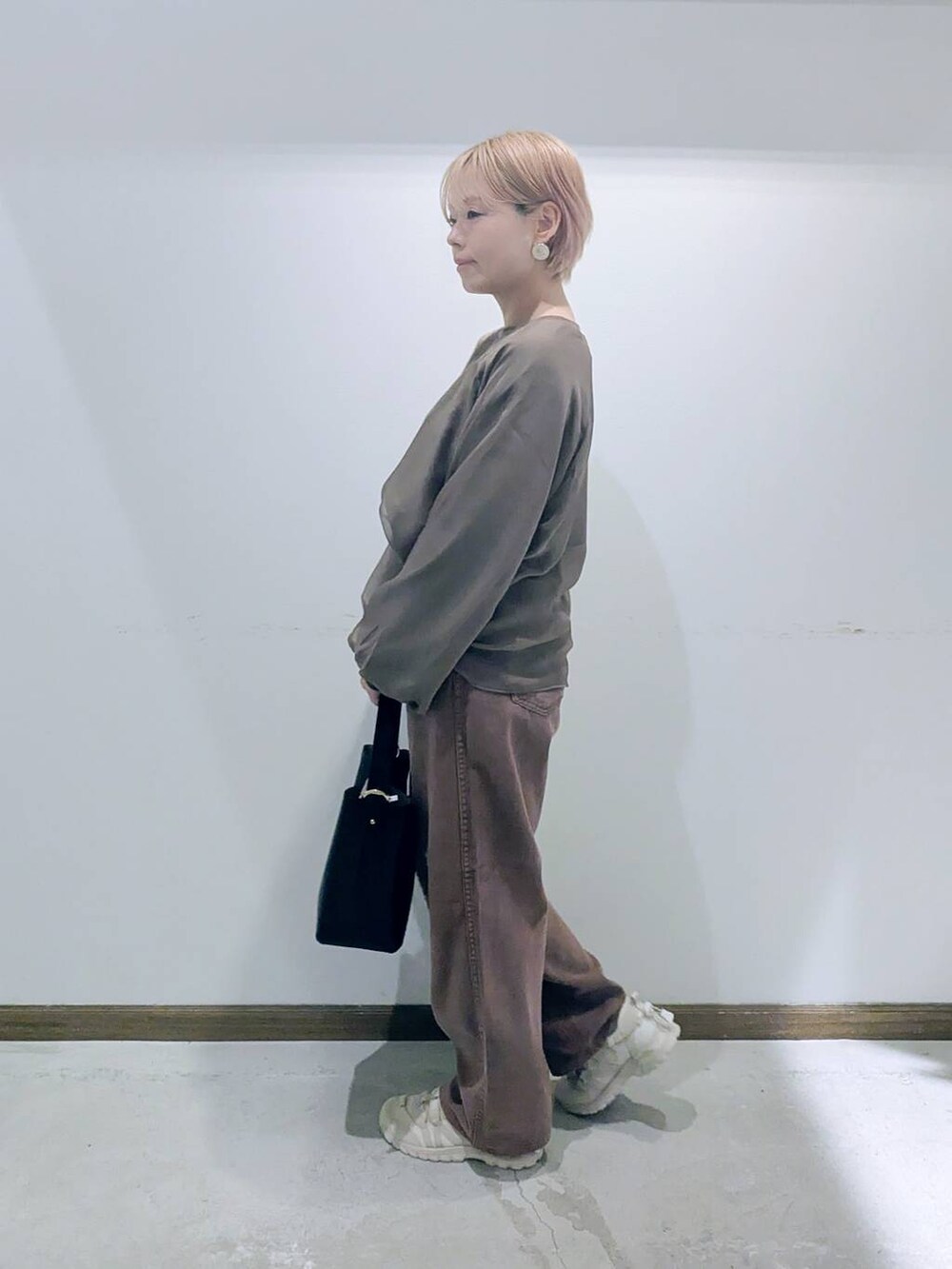 ブラック系のショルダーバッグ、ブラウン系のデニムパンツ、ブラウン系のTシャツ/カットソーを着用したレディースの秋コーディネートの4枚目の写真