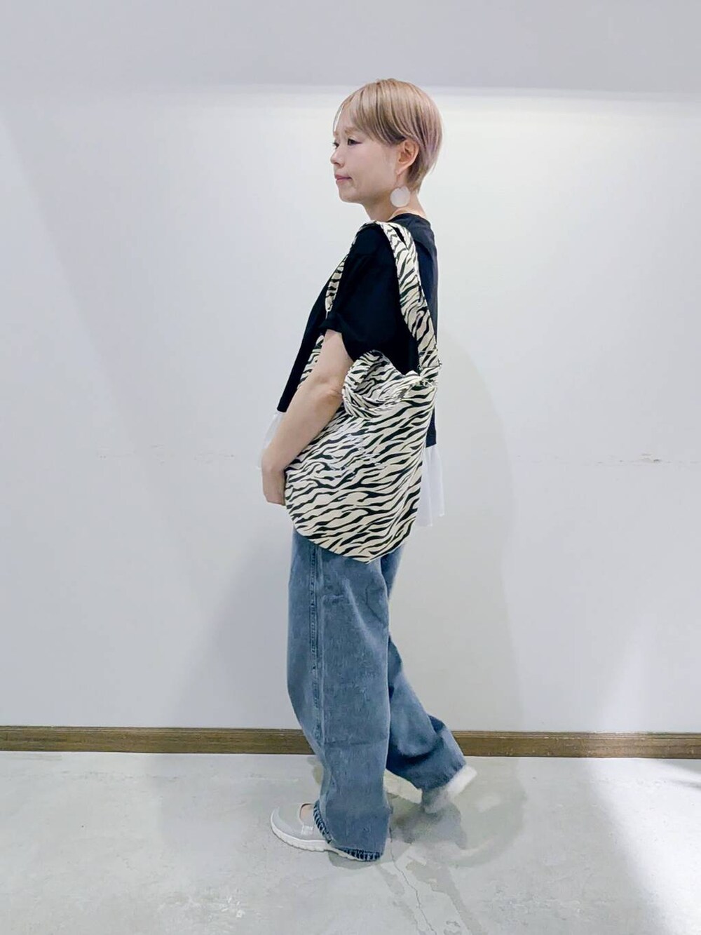 グレー系のスニーカー、その他のトートバッグ、ブルー系のデニムパンツを着用したレディースの夏コーディネートの2枚目の写真