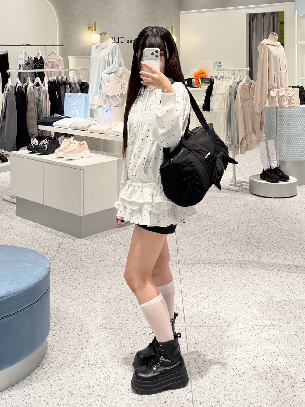 ホワイト系のパーカー、ブラック系のスカート、ブラック系のボストンバッグを着用したレディースの春コーディネートの2枚目の写真